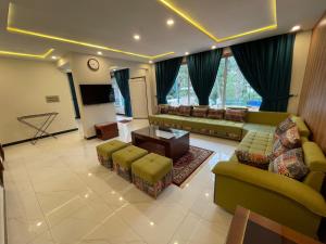 a living room with couches and a flat screen tv at Sangha Cottage in Abbottābād