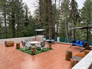 a patio with chairs and tables and a blue couch at Sangha Cottage in Abbottābād