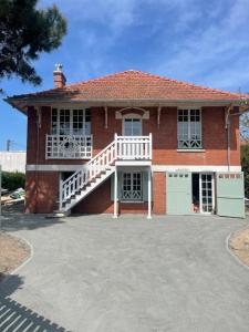 a red brick house with a white porch and a garage at La Maison Léon in Biscarrosse