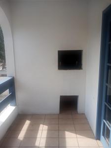 a room with a white wall with a flat screen tv at Pousada Del Mare in Florianópolis +6 photos