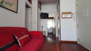 a living room with a red couch and a television at Vivenda Ponte Romana in Padrón