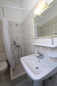 Un baño con lavabo, inodoro y espejo. en Casa alle terme, en Loutra Edipsou