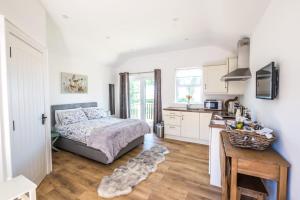 a bedroom with a bed and a kitchen with a dog laying on the floor at The Stables at Ballygraffan in Comber