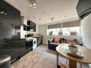 a kitchen and living room with a table and a couch at Central Sheffield 1 Bed Flat, Sleeps 3, City Views, Full Kitchen in Midland