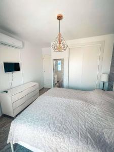 Un dormitorio blanco con una cama y un televisor. en Elegance Harmony Haven in Pinar, en 