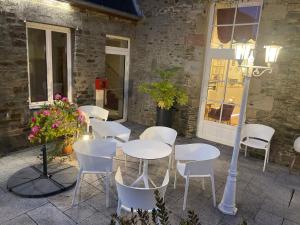 a group of white tables and chairs on a patio at Hôtel Victor Hugo in Pontorson