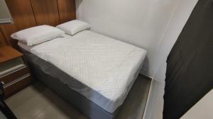 a small bed with two pillows on it in a room at Studio 4 novo completo com wi-fi e estacionamento in Curitiba