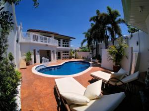 a backyard with a pool and chairs and a house at Villa James in Tarlac