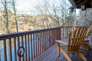 a rocking chair sitting on the deck of a cabin at Coyotes Rest Lake Lucerne 8 in Eureka Springs +18 photos