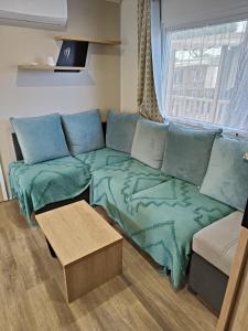 a living room with a couch with green sheets at Mobil home clim 3 chambres à 100m de la plage in Canet-en-Roussillon +7 photos