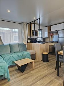 a living room with a couch and a kitchen at Mobil home clim 3 chambres à 100m de la plage in Canet-en-Roussillon
