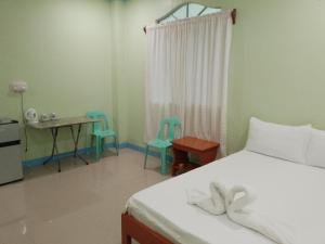 a bedroom with a bed and two chairs and a table at Hidden Valley Guest House in Malapascua Island