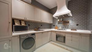 a kitchen with white cabinets and a washer and dryer at نزل سدن in Quai