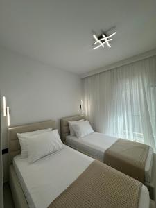 two beds in a small room with a window at Armonia Apartment in Pefkohori