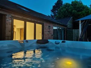 a swimming pool in front of a house at night at The Cowshed - Luxury Barn with Hot Tub in Bromsgrove