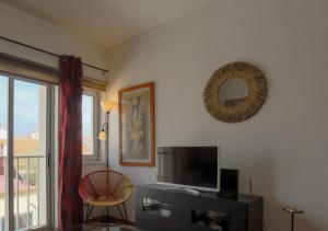 a living room with a tv and a mirror at Casa de Férias T2_Frente de praia in São Martinho do Porto