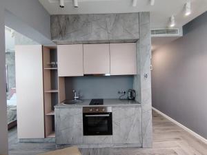 a kitchen with white cabinets and a stove top oven at Grand Marina Apartments Batumi in Batumi