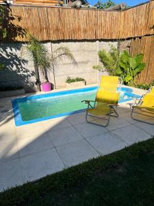 two yellow chairs sitting next to a swimming pool at La Casita in San Antonio de Areco