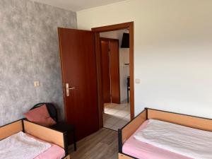a room with two beds and a door to a hallway at Ferienwohnungen Im Hirschgrund in Frohnhausen +1 photo