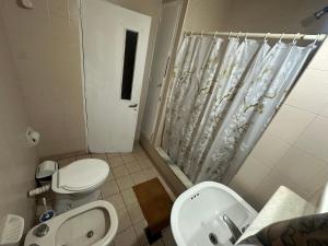 a bathroom with a toilet and a sink and a shower at Departamento centrico in Santiago del Estero +6 photos