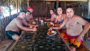 a group of men sitting around a table eating food at isla de san blas in Warsobtugua
