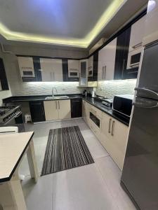 a large kitchen with white cabinets and a rug at شقه مفروشه 3 غرف امام سيتي ستارز in Cairo