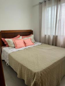 a bed with pink and white pillows on it at linda casa alugo diaria ou mensal para empresa in Governador Valadares