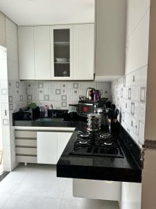 a kitchen with white cabinets and a black counter top at linda casa alugo diaria ou mensal para empresa in Governador Valadares