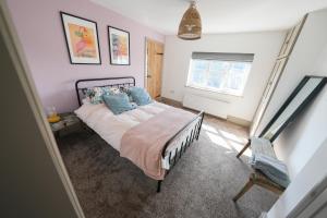 a bedroom with a bed with blue pillows and a window at Plumtree Cottage in Farnsfield