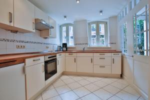 a kitchen with white cabinets and windows at Ferienwohnung Coco in Lübeck