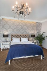 a bedroom with a blue bed and a chandelier at Moris Boutique Beach Hotel in Gdańsk