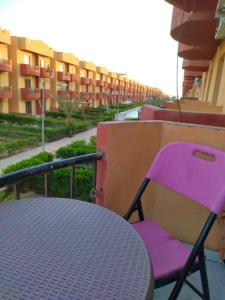 a purple chair sitting next to a table on a balcony at استوديو مفروش ومكيف في راس سدر -بحر رملي وحمام سباحة- للعائلات الصغيرة فقط in Ras Sedr