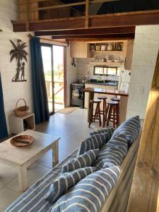 a living room with a couch and a kitchen at Maories in Punta Del Diablo