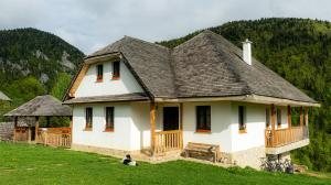 a white house with a gray roof on a green field at Pensiunea Hodăița in Măgura