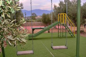a playground with two swings and a slide at VILLA IN THE OLIVE TREES Galaxidi in Galaxidi