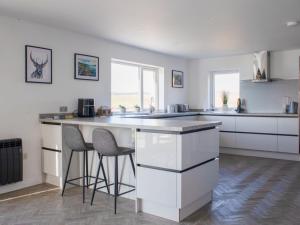 eine Küche mit weißen Schränken und einer Theke mit Stühlen in der Unterkunft Holiday Home Daisy Cottage by Interhome in Eyre + 28 Fotos