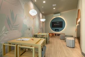 a waiting room with tables and a tv on a wall at Intercity Porto Alegre Aeroporto in Porto Alegre