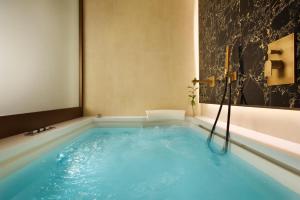 uma banheira de hidromassagem na casa de banho com água azul em FH55 Grand Hotel Palatino em Roma