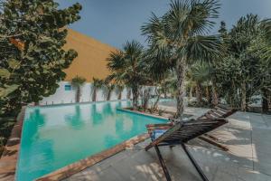 a chair sitting next to a swimming pool with palm trees at Villa Xcambo San bruno in San Bruno