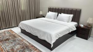 a bedroom with a large bed with white sheets and pillows at شقة المروة in Al ‘Utaybīyah