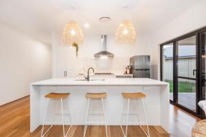 una cocina con una gran isla blanca con taburetes de bar en Pet-friendly. Bright and Spacious Dunsborough Home, en Dunsborough