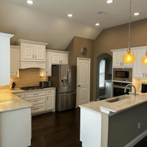 フリスコにあるSpacious 4BR Home in Frisco Ideal for Long Staysの白いキャビネットとステンレス製の電化製品を備えたキッチン