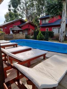 a group of picnic tables next to a swimming pool at Cabaña La Arianna in Santa Teresita