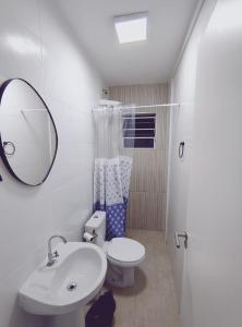 une salle de bain avec un lavabo, des toilettes et un miroir dans l'établissement Casa de Condomínio 350 mts da Praia, à Praia Grande