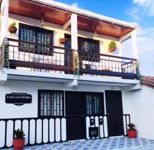 サレントにあるSan Pedro Salento Apartahotelの白い建物(黒いドア、バルコニー付)