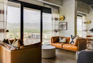 a living room with leather furniture and large windows at Cityscape Peaks Penthouse DT Gym Free parking in Salt Lake City