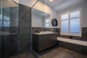a bathroom with a sink and a tub and a mirror at Kawana Retreat - modern Dunsborough holiday haven. in Dunsborough +42 photos