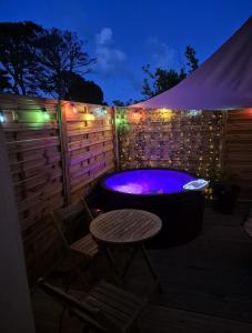 a hot tub with a chair and a table and lights at Romantic room le moutik du bord de mer avec SPA et sauna parking gratuit in Lampaul-Plouarzel