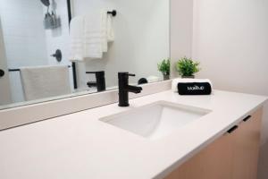 Un baño blanco con lavabo y espejo. en The Downtown Lookout DT Gym free parking, en Salt Lake City