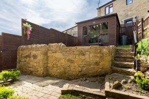 eine steinerne Stützmauer vor einem Haus in der Unterkunft 'Haworth Haven', Warm Winter Cottage Getaway in Haworth + 47 Fotos